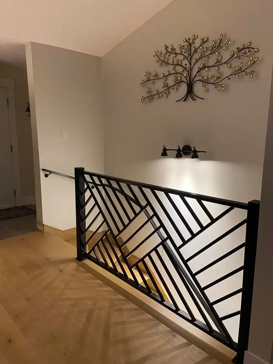 Angled view of geometric herringbone railing showing full pattern with staircase below
