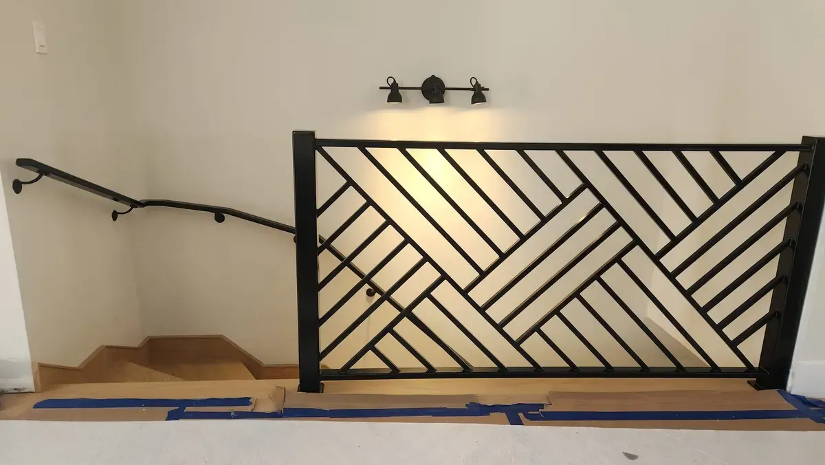 Custom geometric herringbone pattern interior railing in black steel with stair handrail