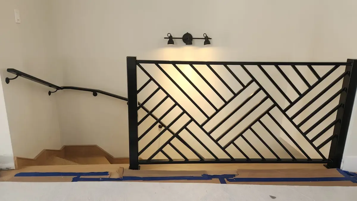 Custom geometric herringbone pattern interior railing in black steel with stair handrail