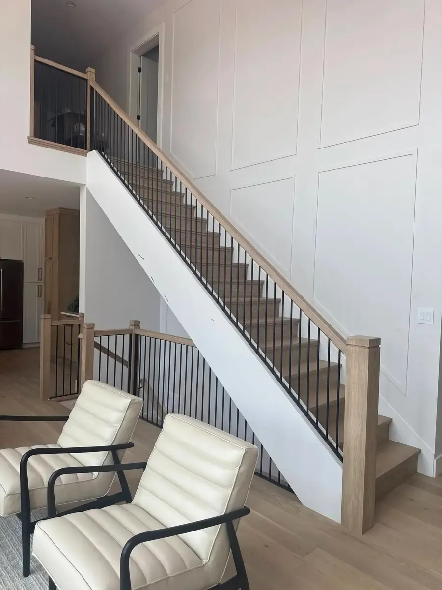 Full living room view of oak and black steel vertical bar railing with modern furniture