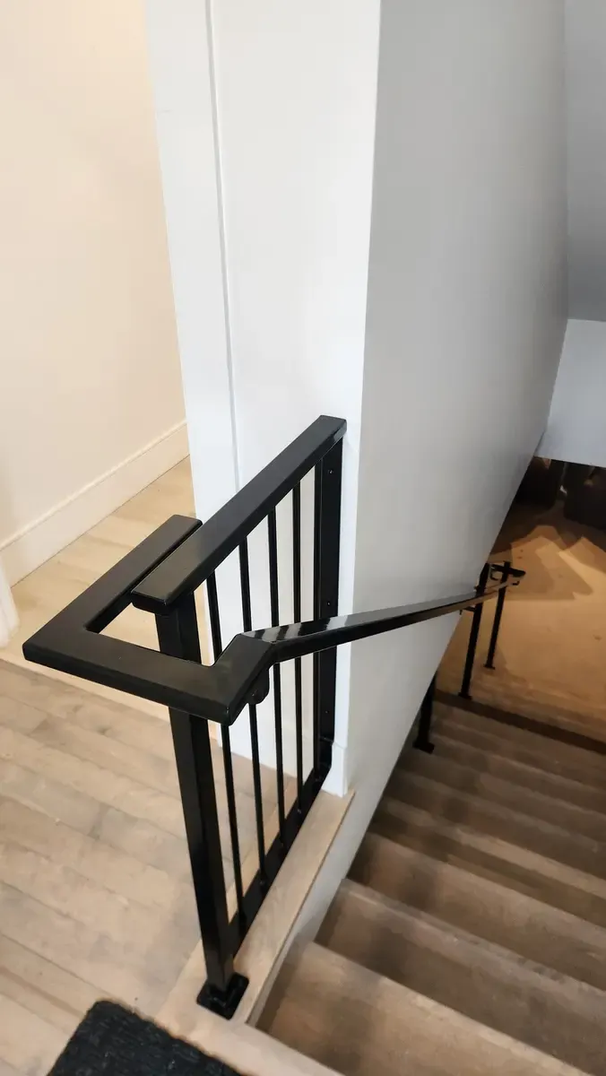 Interior stair railing with vertical bars and geometric corner detail in black steel