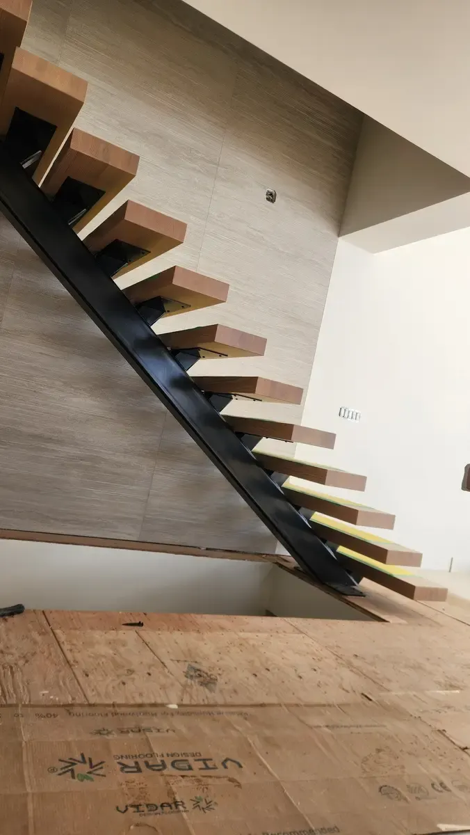 Side angle of luxury floating staircase showing steel spine and wood tread connection detail