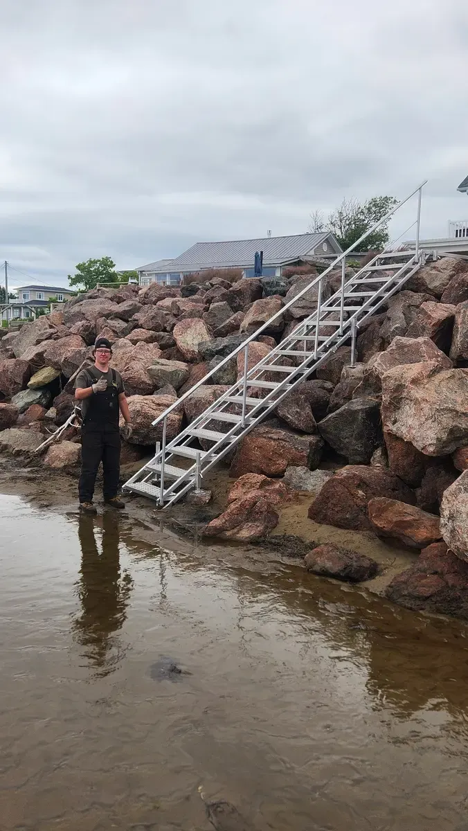 Trevor standing beside completed beach access stairs installation at low tide