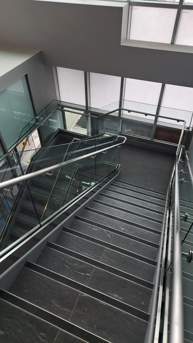 Bird's-eye view of commercial glass and stainless steel railing on multi-flight staircase