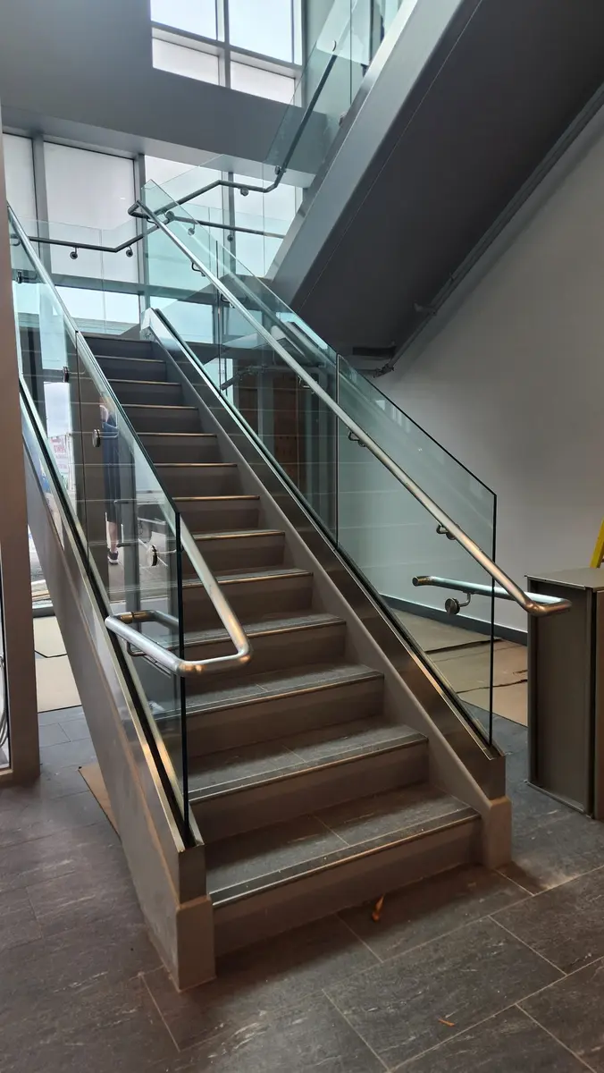 Commercial stainless steel and glass railing system on wide staircase