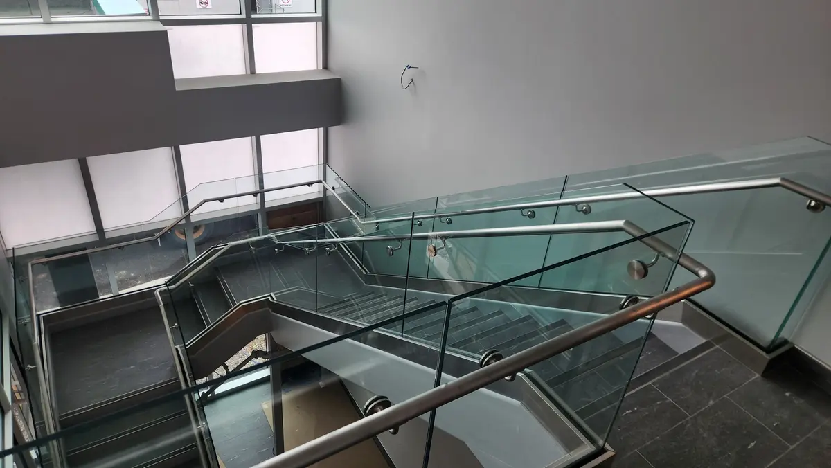 Commercial stainless steel and glass panel railing system, top-down view of stairwell