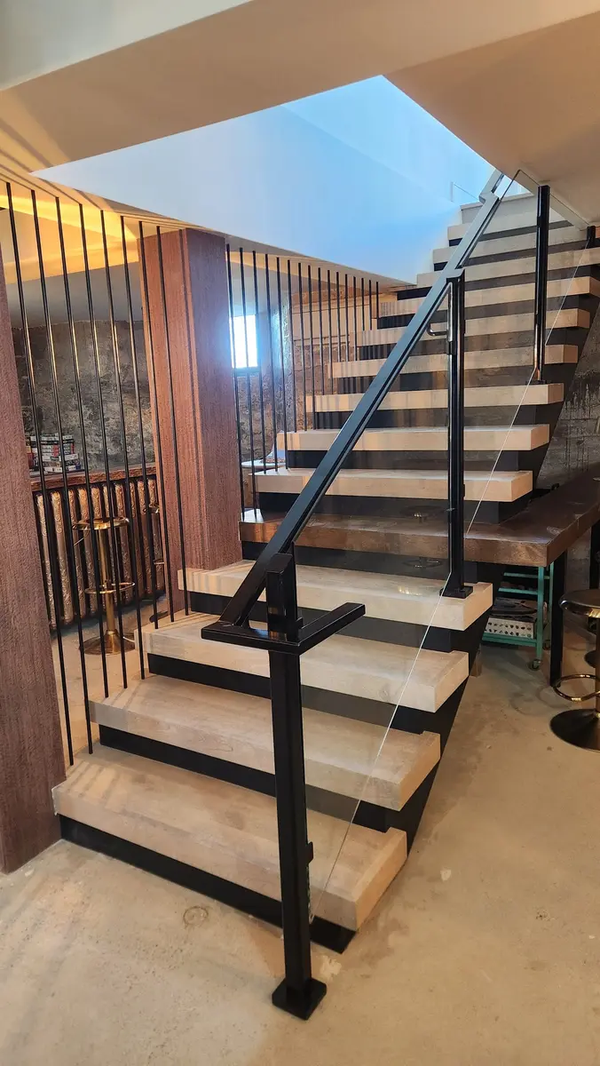 Commercial restaurant stairs with glass panels, vertical steel bars, and wood column accents