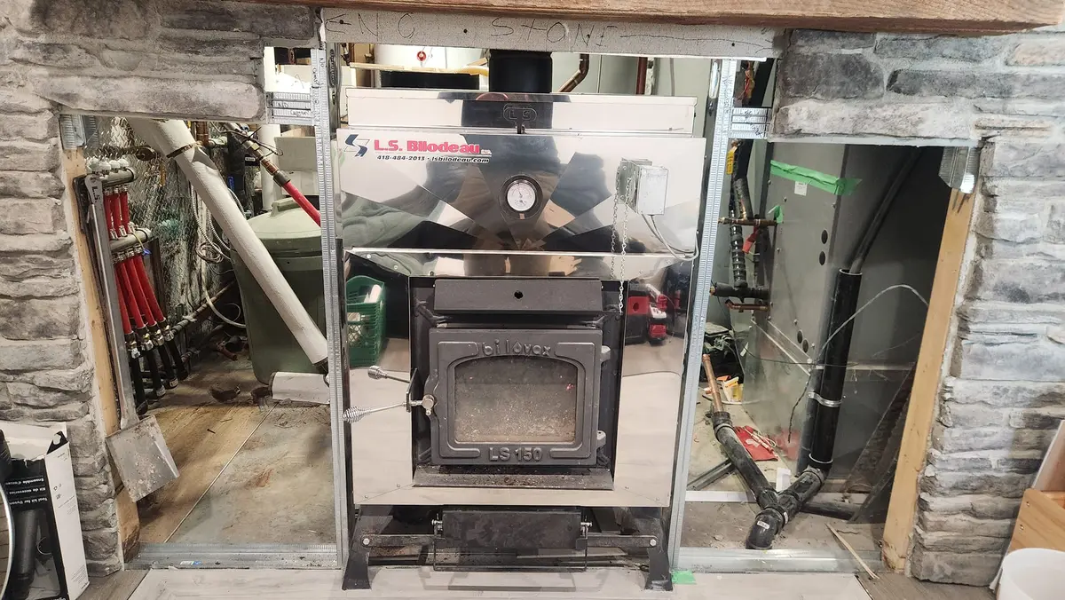 Behind-the-scenes fireplace installation showing steel frame and wood stove connection