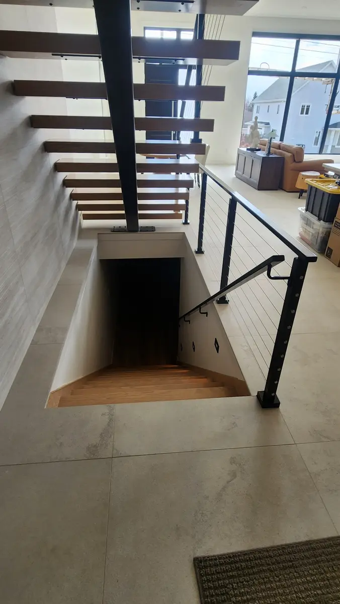 Top-down view of floating stairs with cable railing opening to modern living room