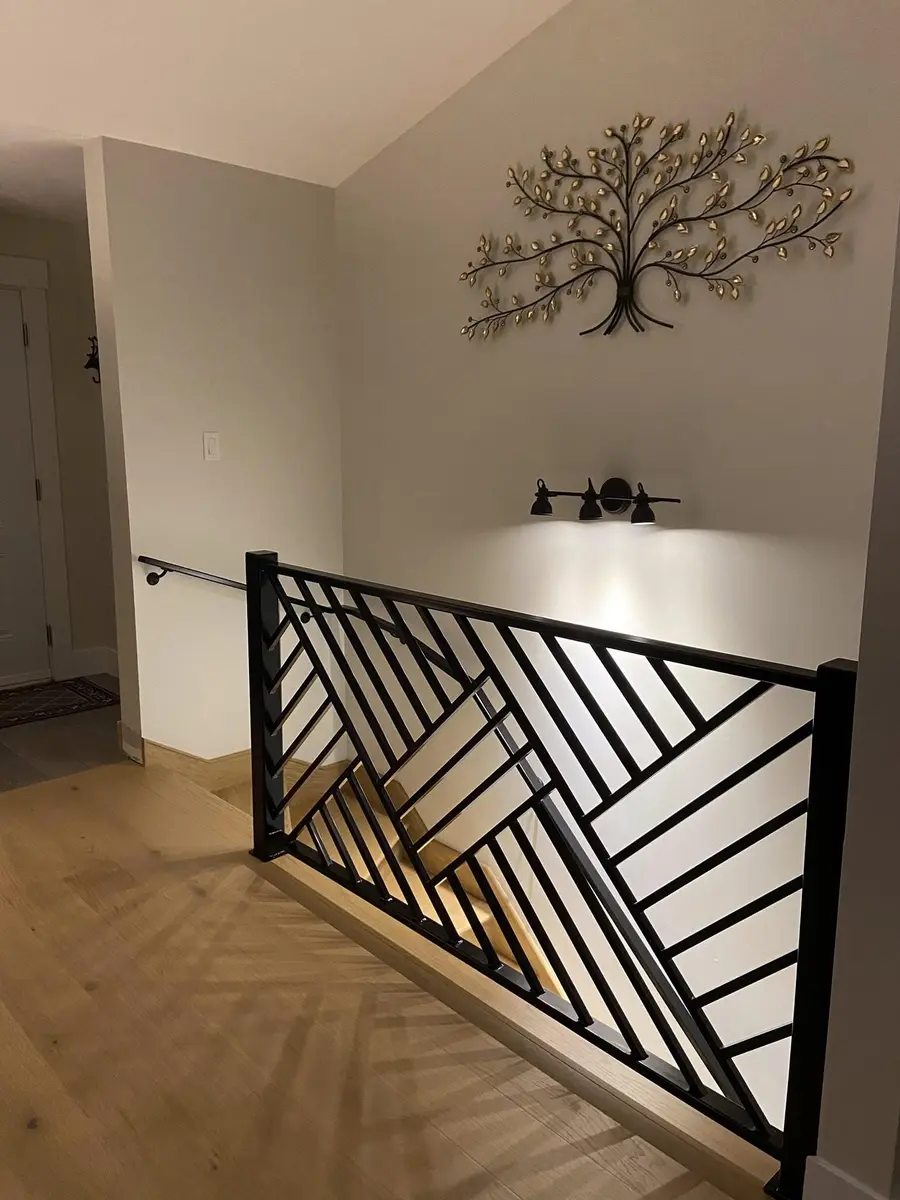 Angled view of geometric herringbone railing showing full pattern with staircase below