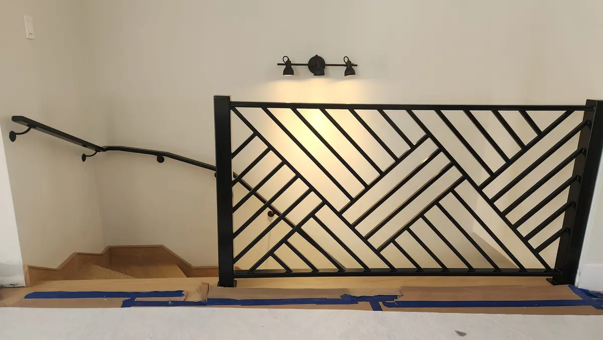 Custom geometric herringbone pattern interior railing in black steel with stair handrail