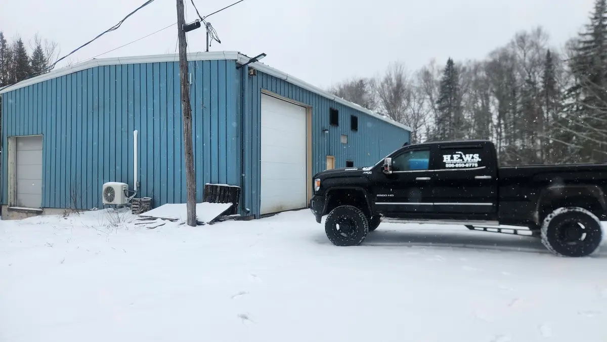 HEWS branded truck parked outside the fabrication shop in winter snow