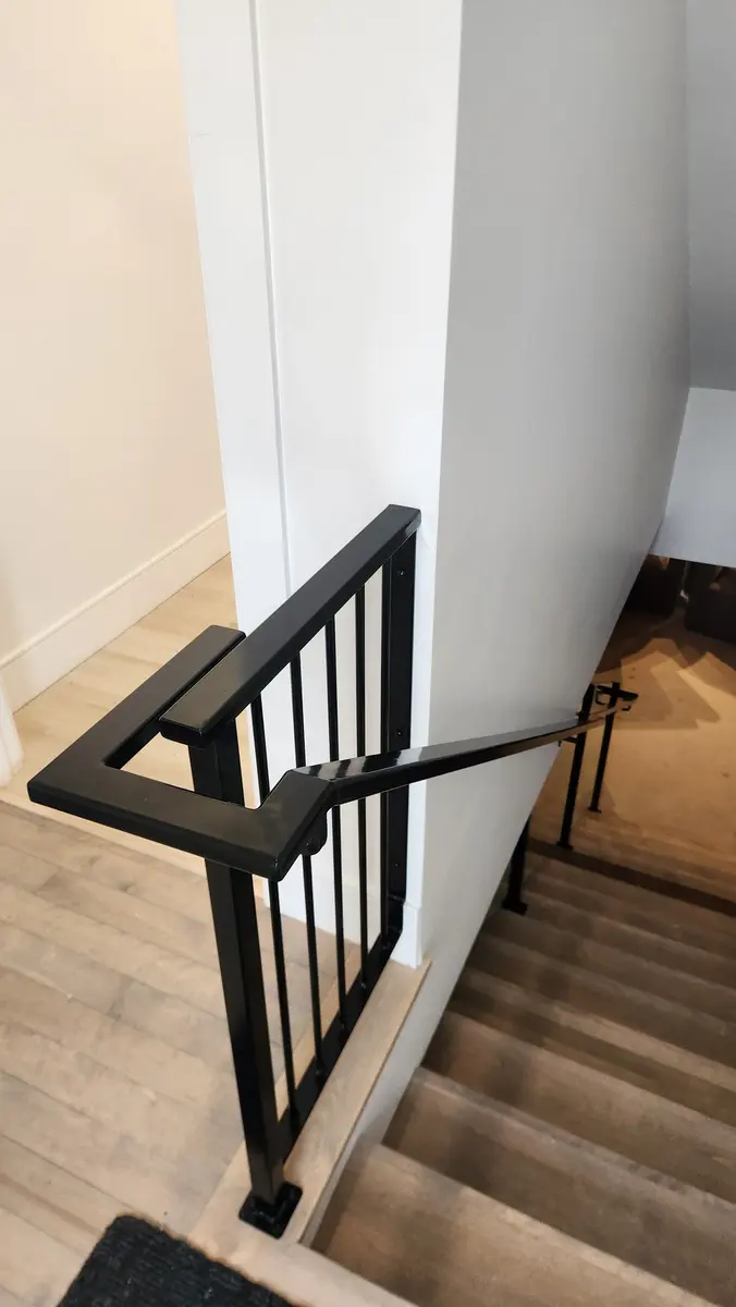 Interior stair railing with vertical bars and geometric corner detail in black steel