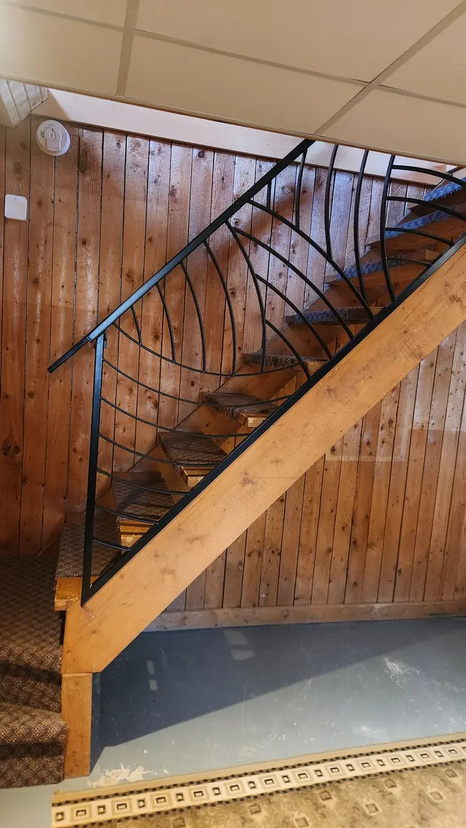 Artistic curved railing viewed from above showing flowing pattern against wood paneling