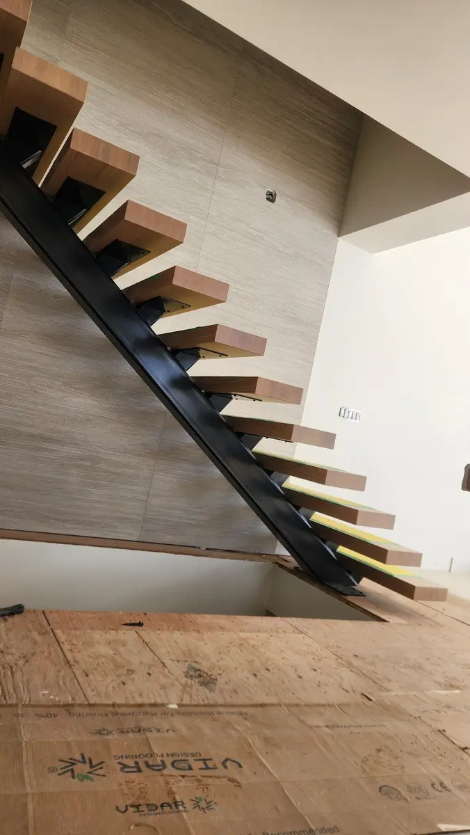 Side angle of luxury floating staircase showing steel spine and wood tread connection detail