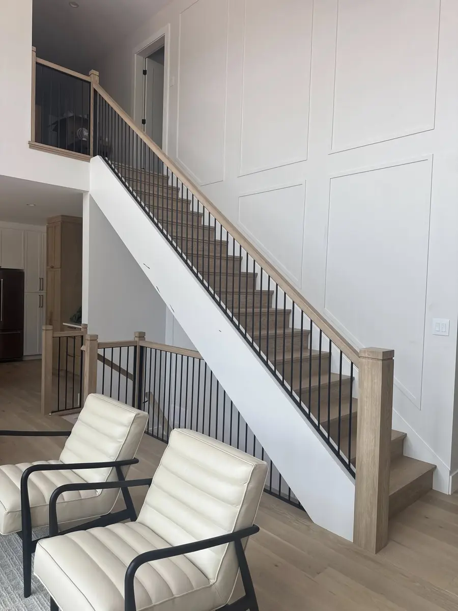 Full living room view of oak and black steel vertical bar railing with modern furniture