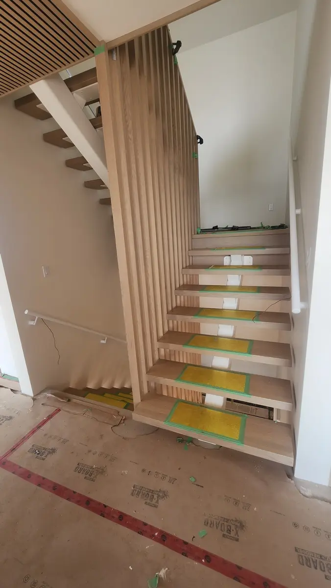 Front view of modern floating stairs with wood slat divider under construction