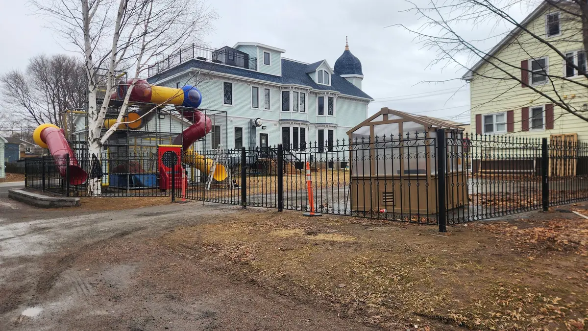 Ornamental iron fence and gate enclosing playground area at heritage property