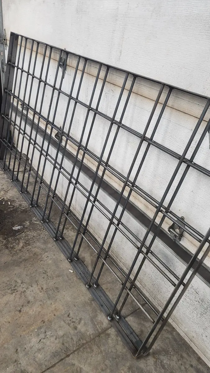 Steel security gate panels laid out in fabrication shop before finishing
