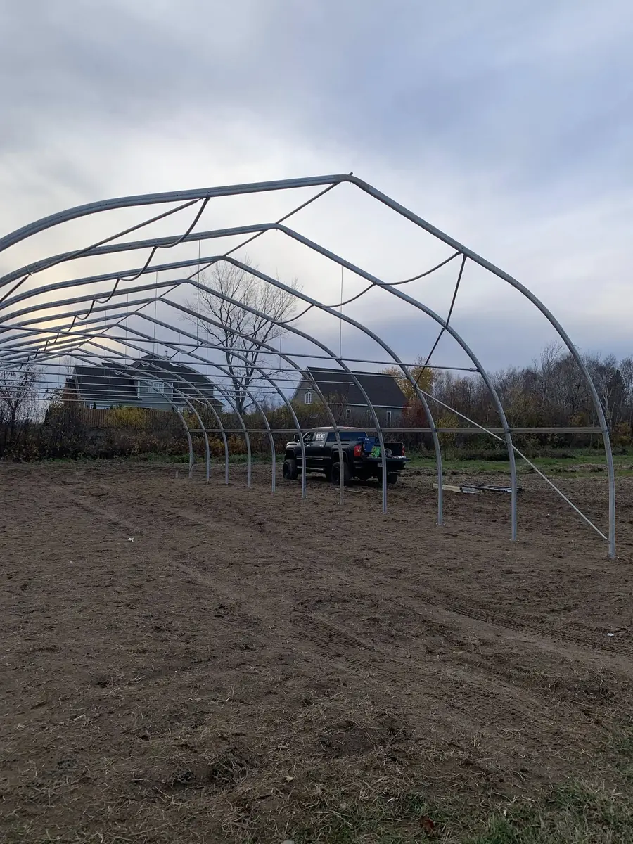 Steel hoop greenhouse frame structure under construction in field