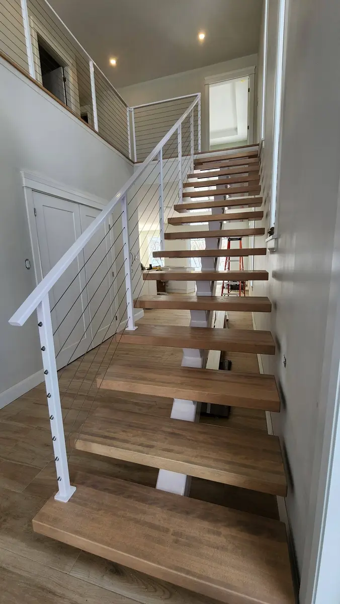 White cable railing along second-floor hallway overlooking main floor